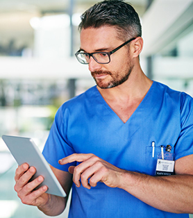 male nurse in a blue scrub looking at the tablet